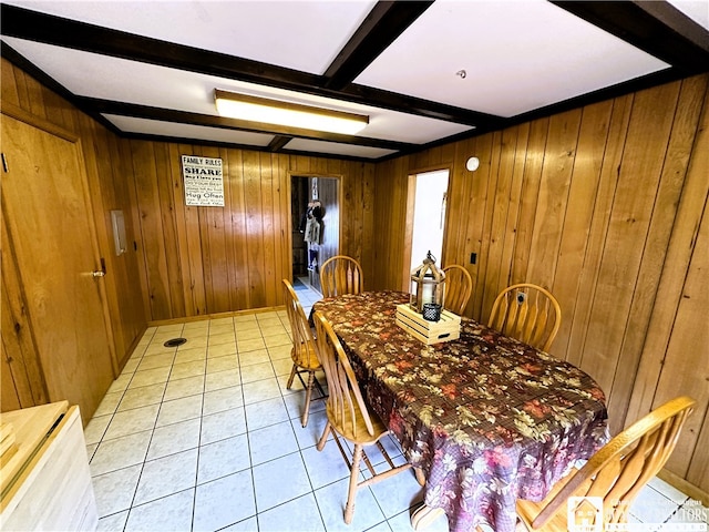 dining space featuring beam ceiling, wooden walls, and light tile patterned floors