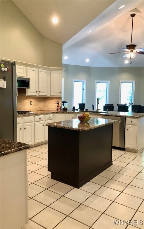 kitchen with appliances with stainless steel finishes, light tile patterned flooring, a peninsula, and white cabinetry