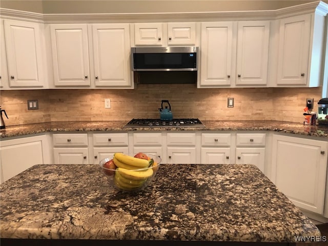 kitchen with appliances with stainless steel finishes, white cabinetry, and tasteful backsplash