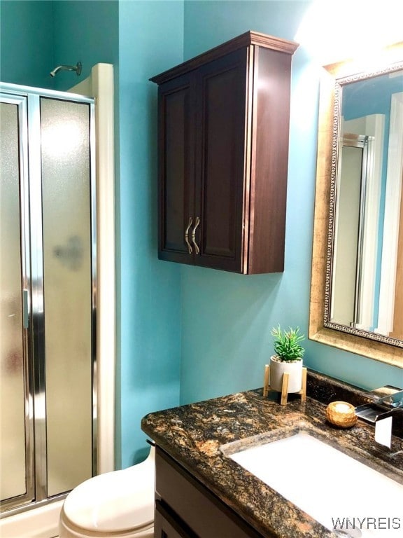 bathroom featuring a stall shower, vanity, and toilet