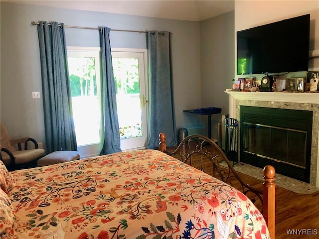 bedroom with a premium fireplace and wood finished floors