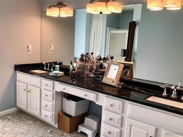 full bath featuring baseboards, double vanity, a sink, and tile patterned floors