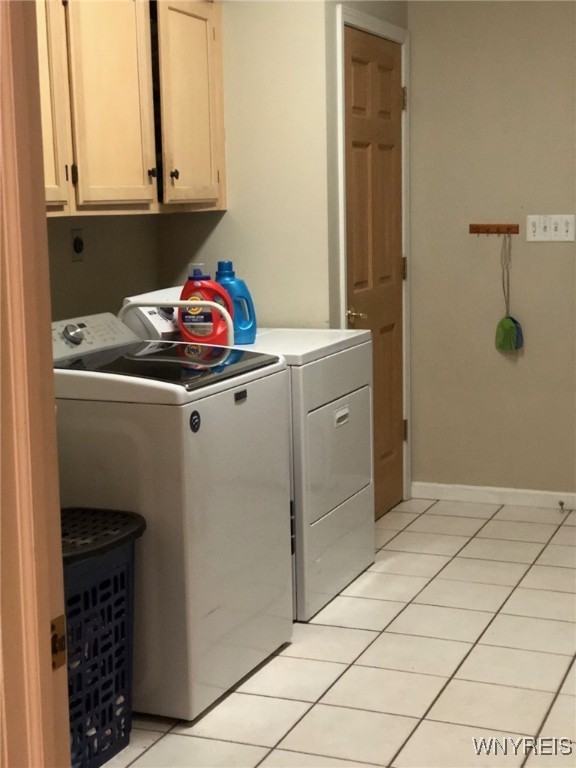 laundry area featuring cabinet space, light tile patterned floors, baseboards, and independent washer and dryer