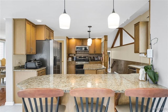 kitchen with a breakfast bar, appliances with stainless steel finishes, decorative light fixtures, and kitchen peninsula