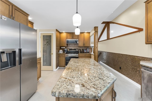 kitchen featuring appliances with stainless steel finishes, a kitchen island, backsplash, decorative light fixtures, and light stone counters