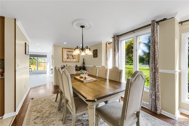 dining space with light hardwood / wood-style floors, crown molding, an inviting chandelier, and plenty of natural light