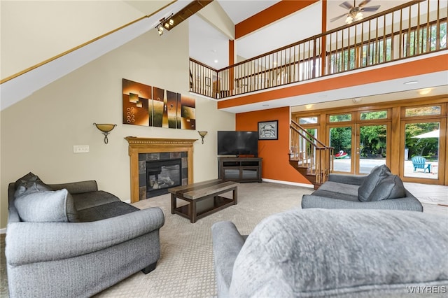 carpeted living room with french doors, a tiled fireplace, high vaulted ceiling, and ceiling fan