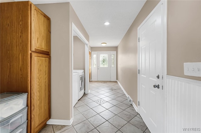 entryway featuring independent washer and dryer and light tile patterned flooring