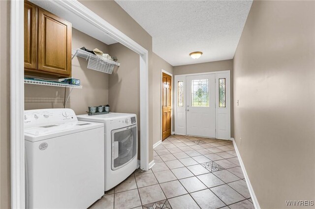 clothes washing area featuring washer and dryer, a textured ceiling, light tile patterned flooring, and cabinets