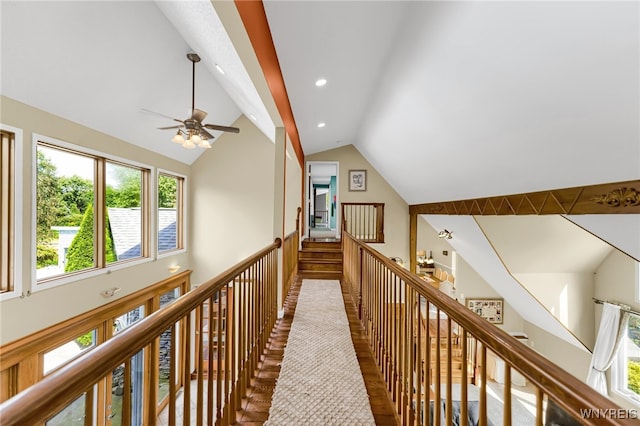 hallway with a healthy amount of sunlight, hardwood / wood-style flooring, and high vaulted ceiling