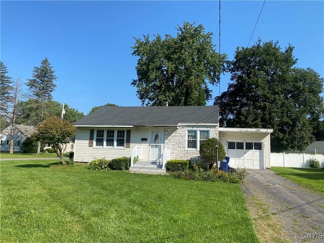 view of front of house featuring stone siding, an attached garage, fence, and a front yard