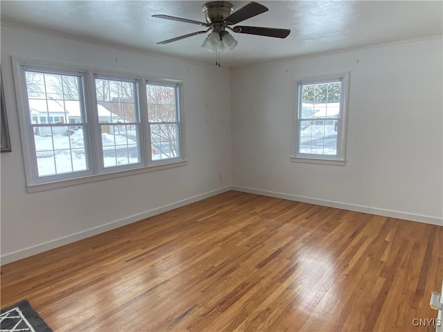 empty room with ornamental molding, light wood-style flooring, and baseboards