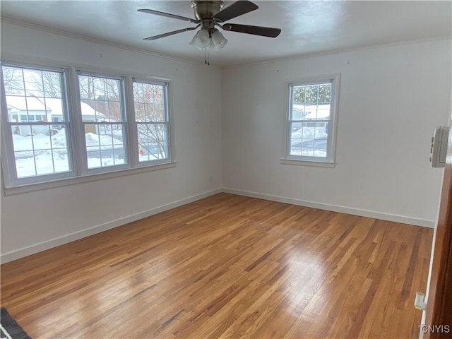 spare room with light wood-style floors, a ceiling fan, baseboards, and crown molding