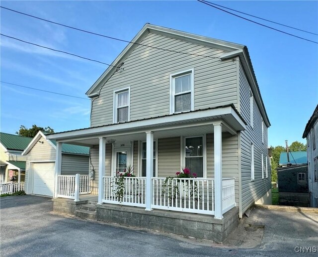 view of front facade with a porch, a garage, and an outbuilding