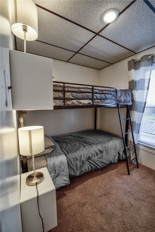 bedroom featuring dark colored carpet and a drop ceiling