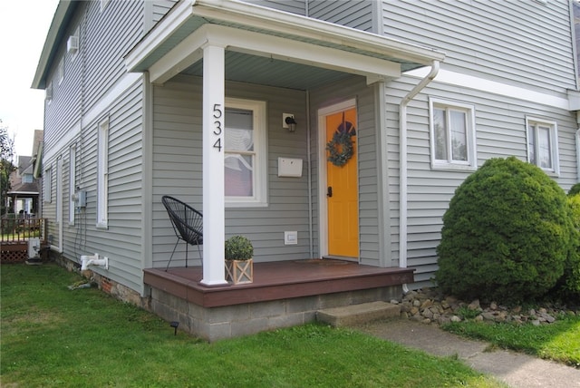 view of exterior entry featuring a lawn and a porch