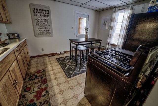 kitchen featuring light tile patterned flooring, a wealth of natural light, a drop ceiling, and gas stove