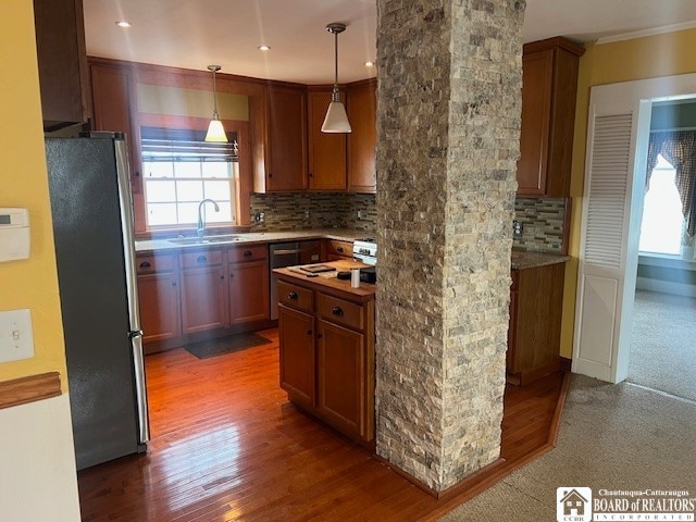 kitchen featuring stainless steel fridge, pendant lighting, dark wood-type flooring, sink, and decorative backsplash