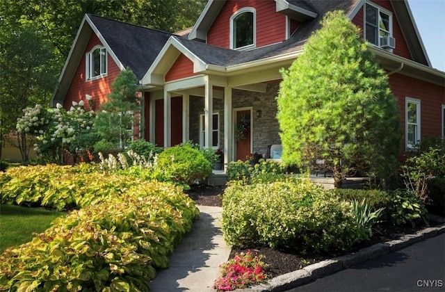 view of front of home featuring a porch, stone siding, and roof with shingles