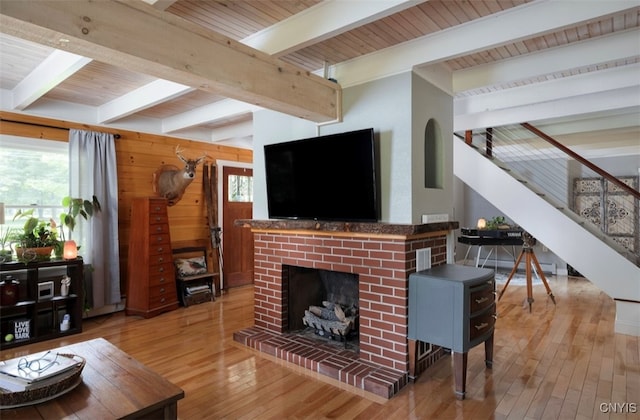 living room with a fireplace, beamed ceiling, and wood-type flooring