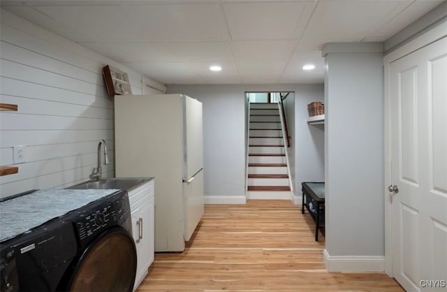 kitchen with light hardwood / wood-style floors, white cabinetry, sink, white fridge, and washer / dryer