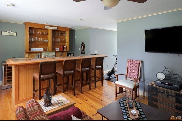 bar featuring light wood-type flooring, crown molding, wine cooler, and ceiling fan