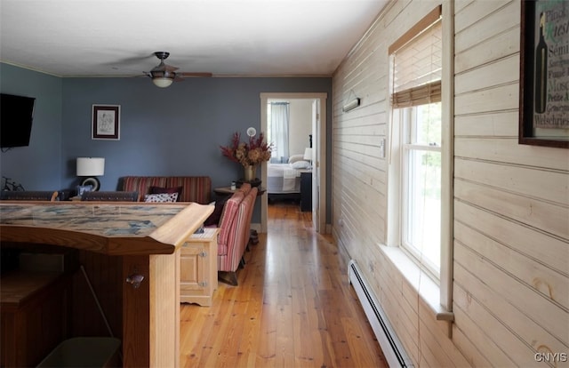 dining room featuring a wealth of natural light, ceiling fan, a baseboard heating unit, and light wood-type flooring