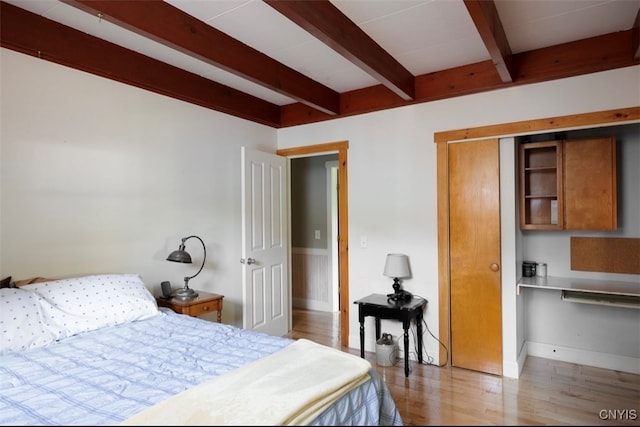 bedroom featuring beamed ceiling and wood-type flooring