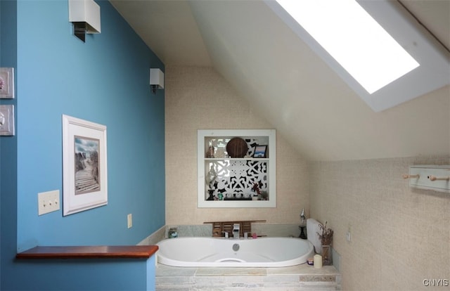 bathroom featuring vaulted ceiling with skylight and a relaxing tiled tub