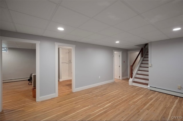 basement featuring a paneled ceiling and light hardwood / wood-style floors