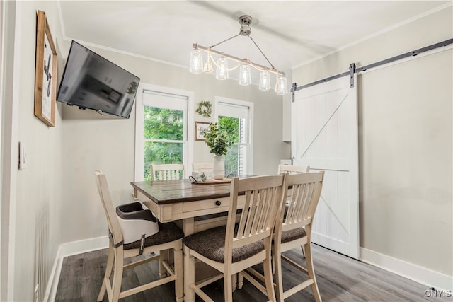 dining area with a barn door, wood-type flooring, and ornamental molding