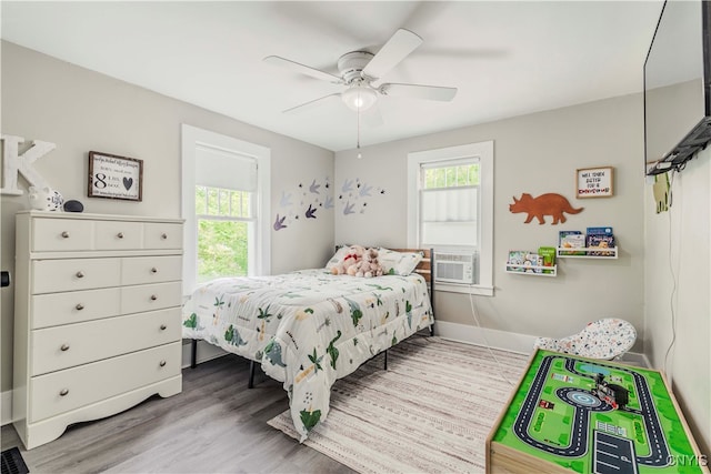 bedroom with multiple windows, cooling unit, ceiling fan, and light hardwood / wood-style floors