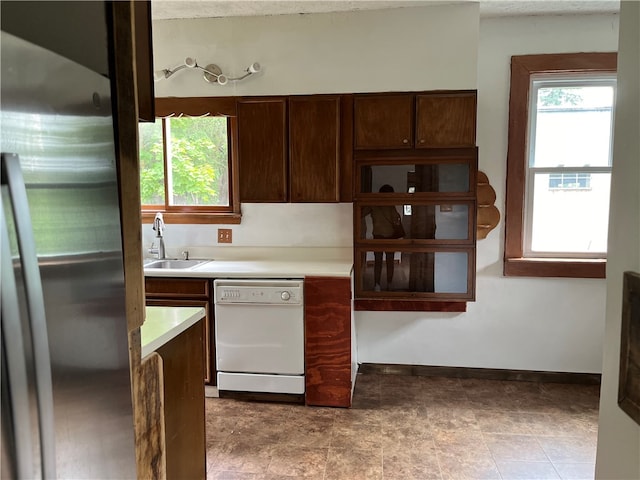 kitchen with dark brown cabinets, white dishwasher, stainless steel refrigerator, sink, and light tile patterned flooring