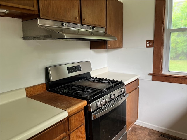 kitchen featuring dark tile patterned flooring, stainless steel range with gas stovetop, and a healthy amount of sunlight