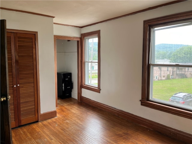 unfurnished bedroom featuring crown molding and wood-type flooring