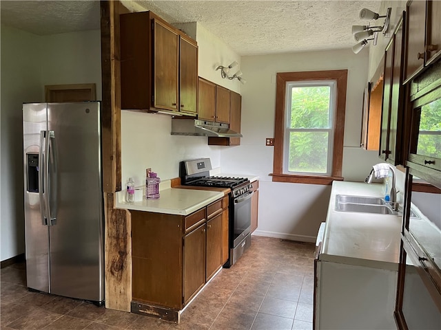 kitchen featuring sink, stainless steel appliances, dark tile patterned floors, and a textured ceiling