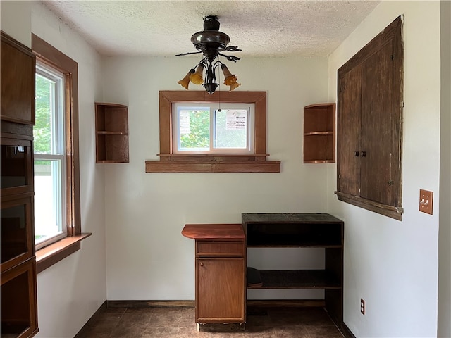 interior space featuring dark tile patterned flooring, ceiling fan, a textured ceiling, and a healthy amount of sunlight