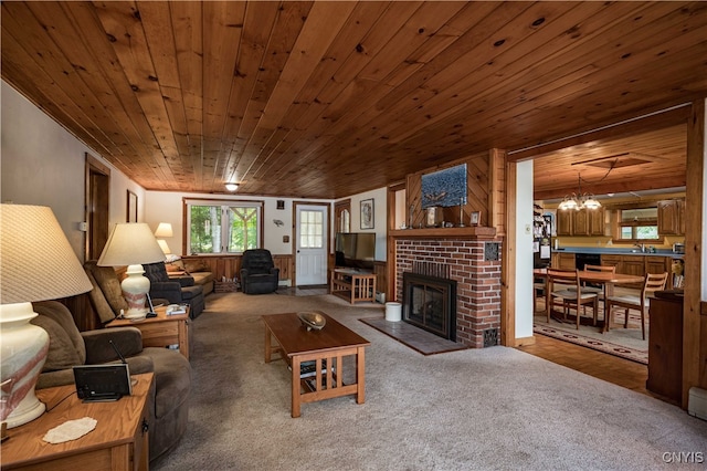 carpeted living room with wood ceiling, a chandelier, and a brick fireplace