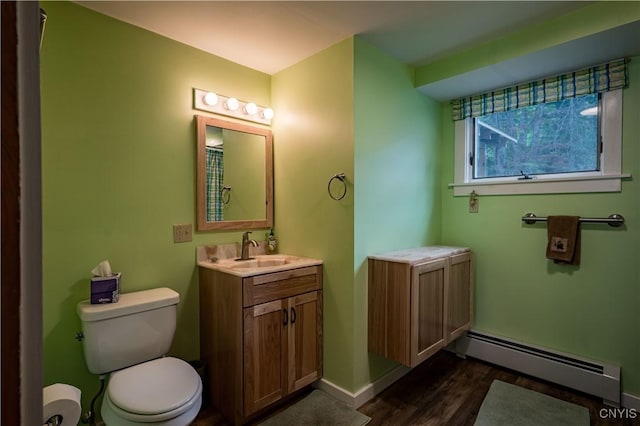 bathroom with toilet, a baseboard heating unit, wood finished floors, vanity, and baseboards