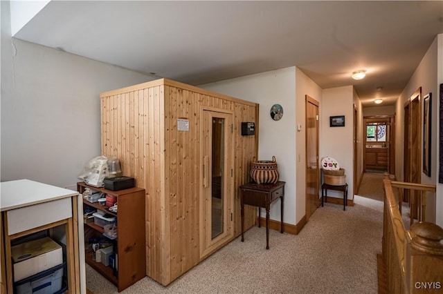 hallway featuring baseboards and light colored carpet