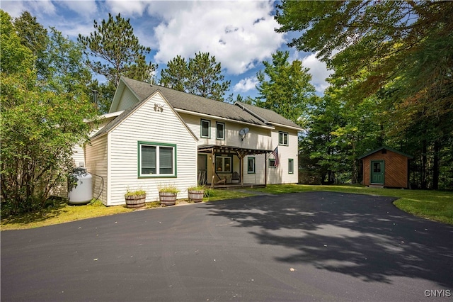 view of front property featuring a pergola and a storage shed