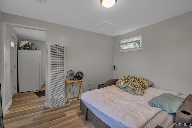 bedroom with white fridge and wood-type flooring