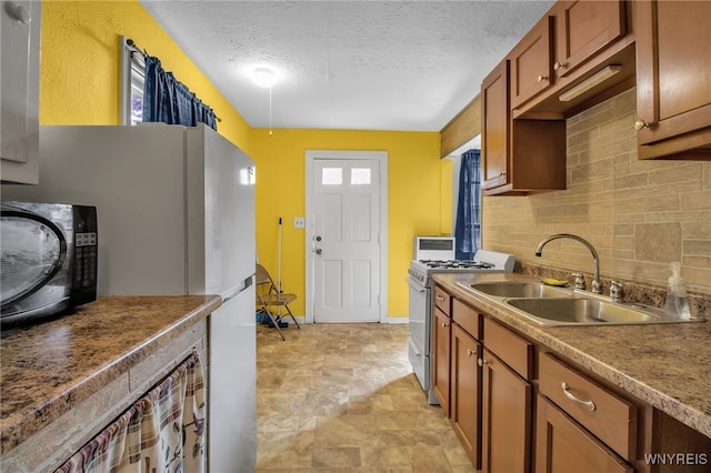 kitchen featuring a textured ceiling, sink, light tile patterned floors, and range with gas cooktop