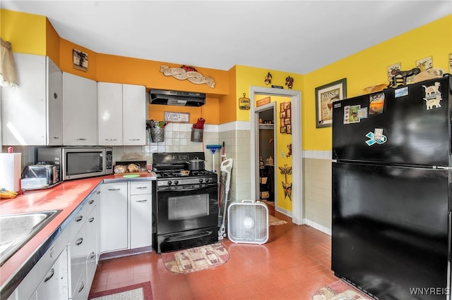 kitchen with black appliances, backsplash, dark tile patterned floors, and white cabinets