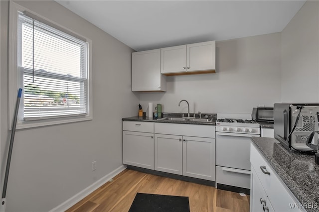 kitchen with white gas stove, sink, light wood-type flooring, and white cabinets