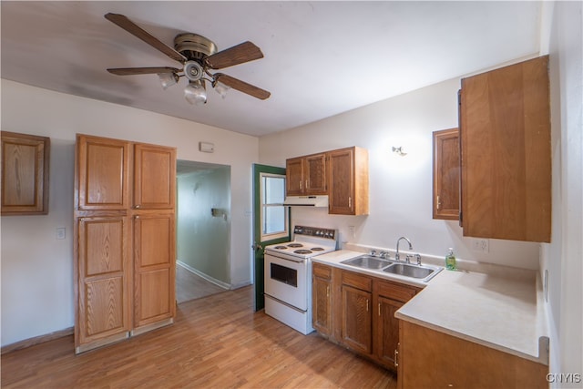 kitchen with brown cabinetry, electric stove, light countertops, under cabinet range hood, and a sink