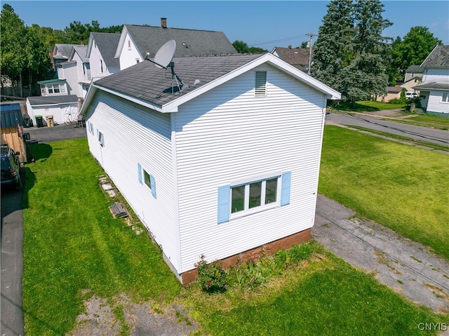 view of home's exterior featuring a residential view, roof with shingles, and a lawn