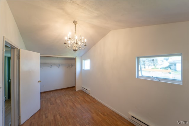 spare room with vaulted ceiling, baseboard heating, wood finished floors, and baseboards