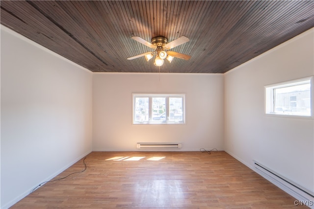 empty room with light wood-style floors, a baseboard radiator, and a wealth of natural light