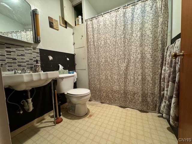 bathroom with a shower with shower curtain, backsplash, and toilet